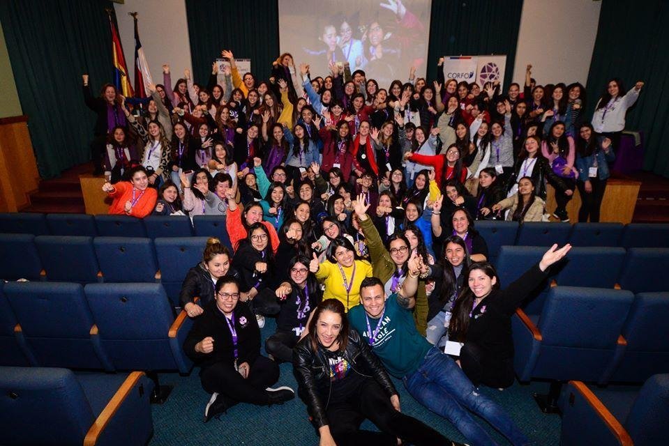 A full auditorium of participants with hands raised