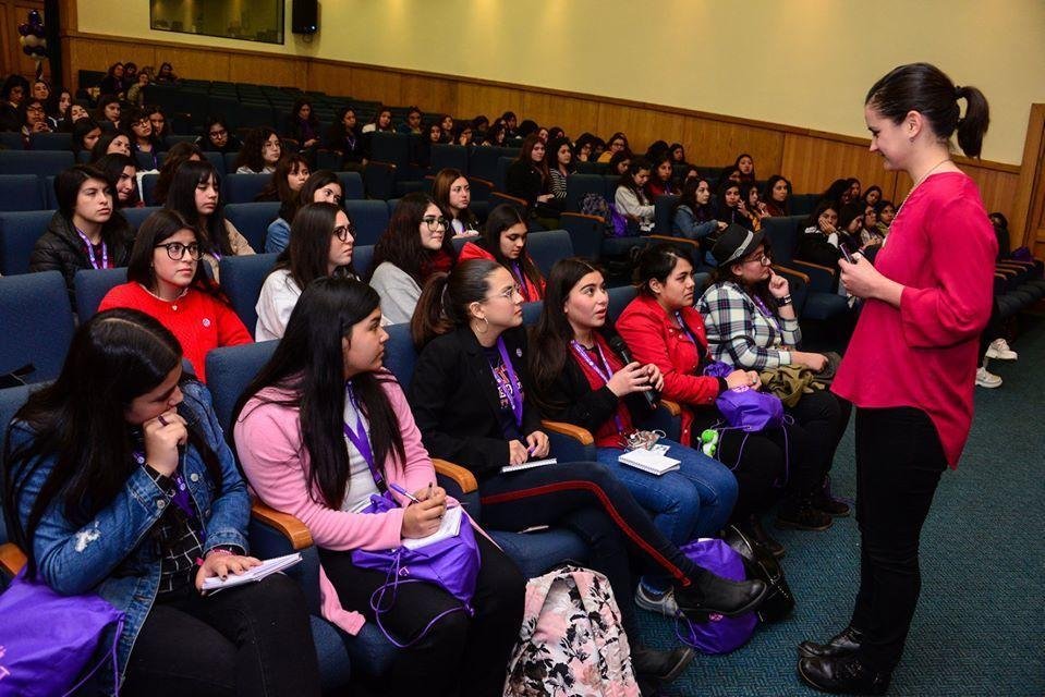 Pilar Dueñas speaking with a full auditorium of young women taking notes